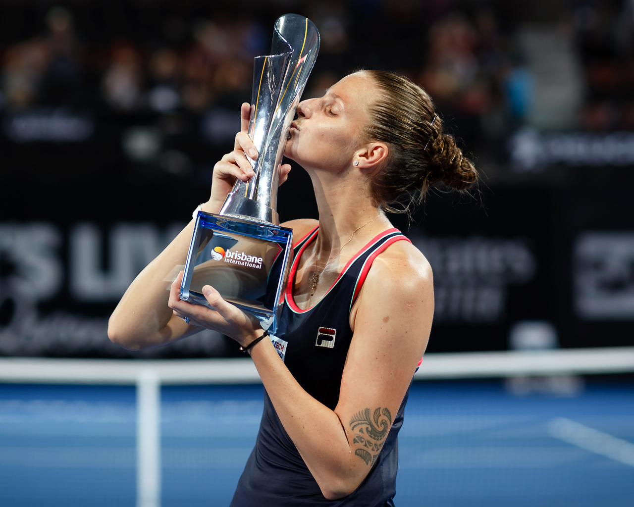 Чешская теннисистка Каролина Плишкова целует кубок на корте