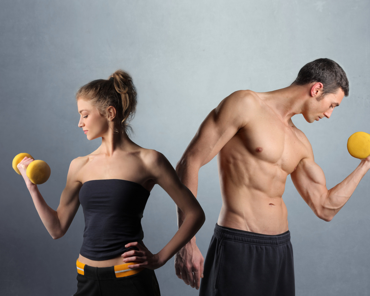 Девушка и парень занимаются спортом с гантелями