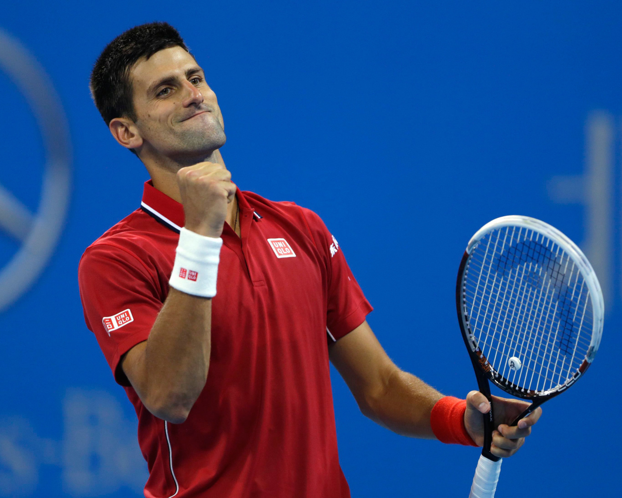 Теннисист Новак Джокович с ракеткой радуется на корте
