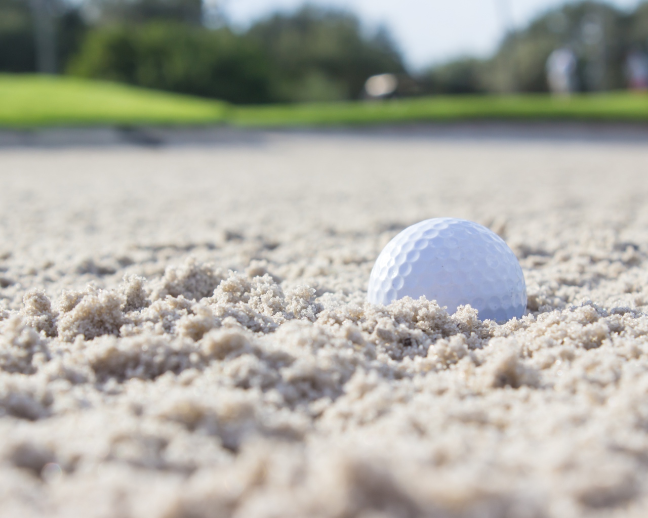 Белый мяч для гольфа лежит на песке