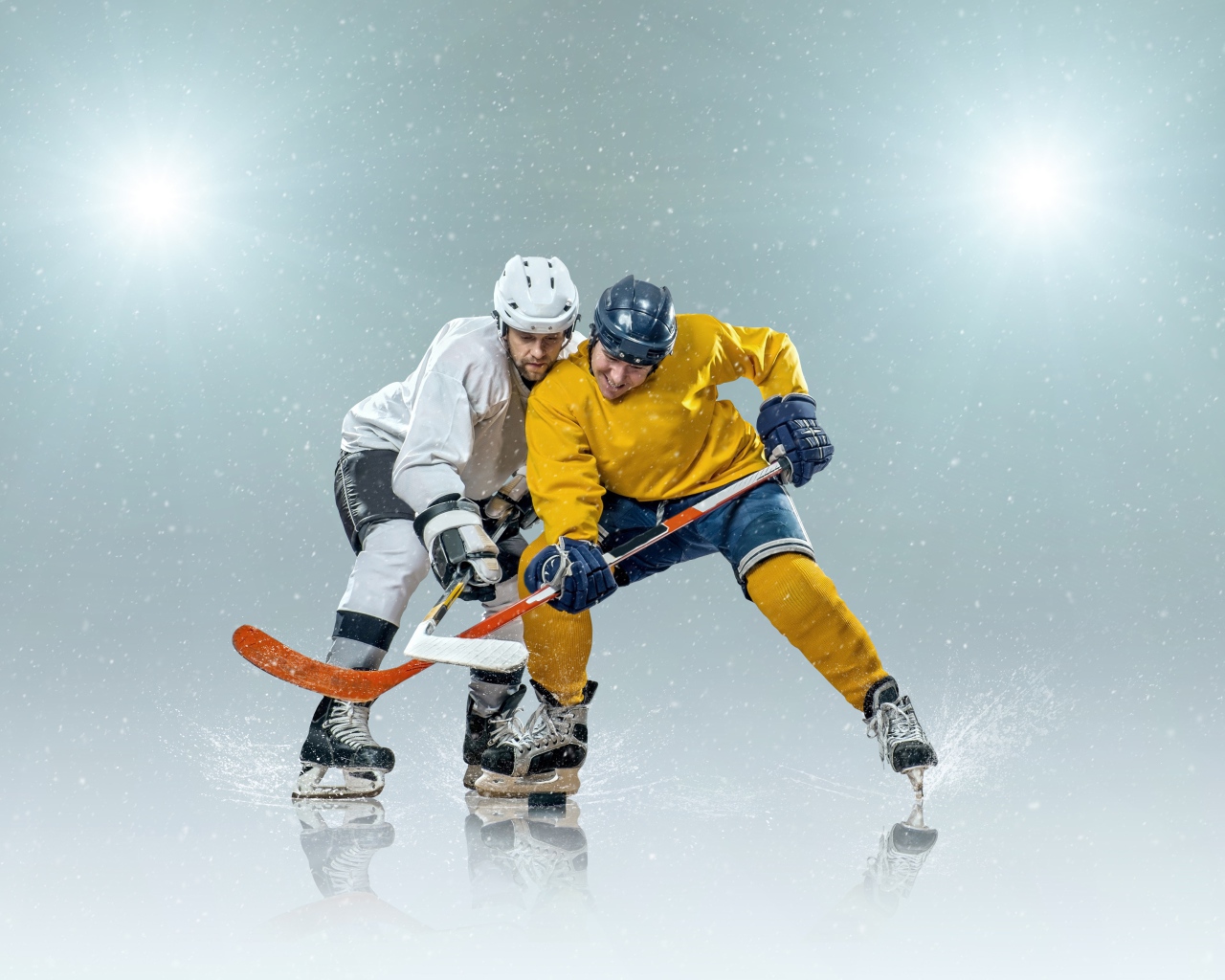 Два спортсмена хоккеиста на льду с клюшками