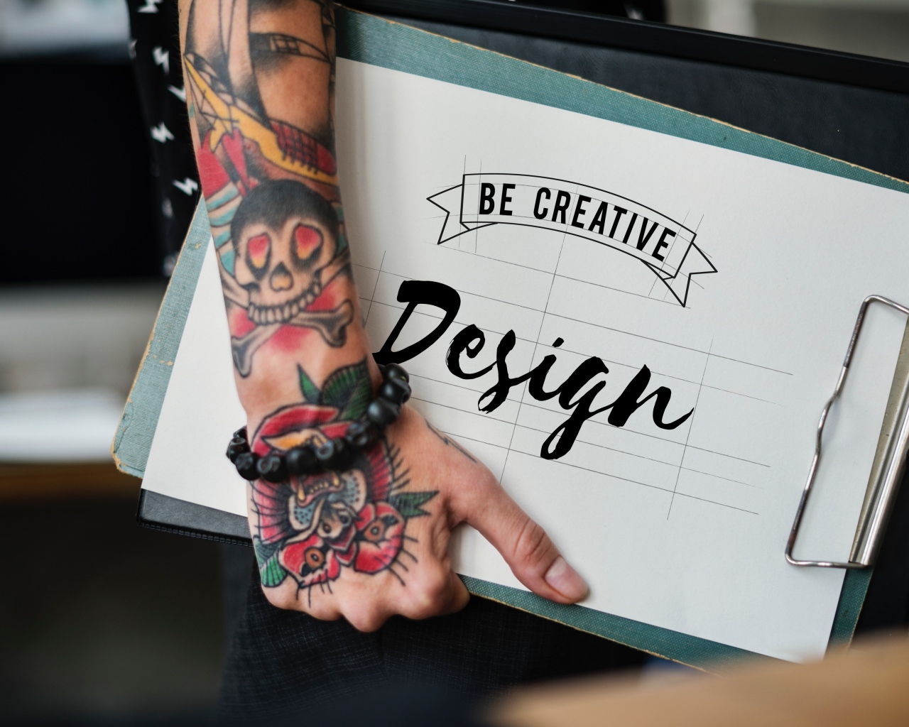 Мужчина с татуировкой на руке держит папку