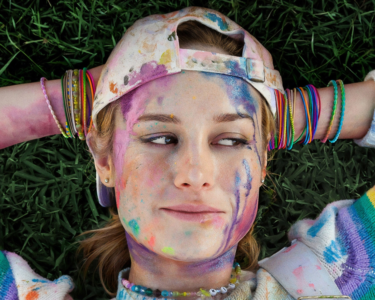 Актриса Бри Ларсон с лицом в краске лежит на траве