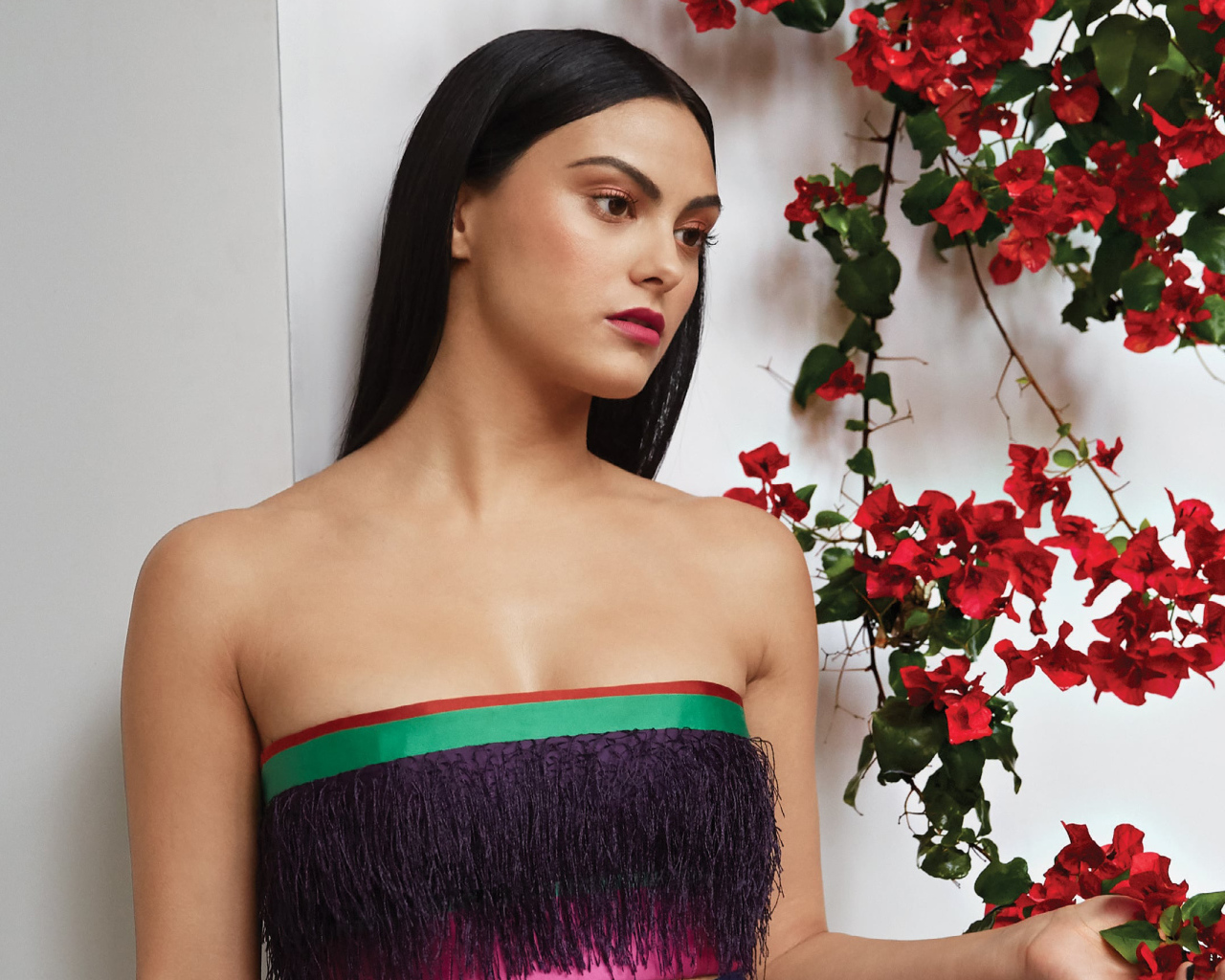 Актриса Камила Мендес стоит у стены с цветами