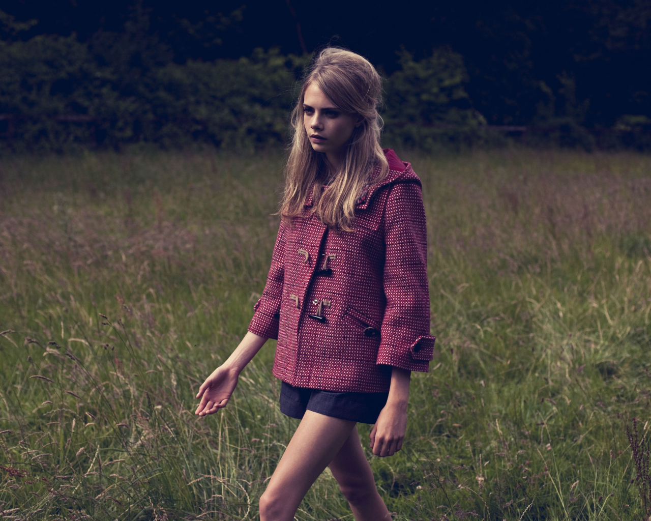 Актриса Кара Делевинь идет по траве в пальто 