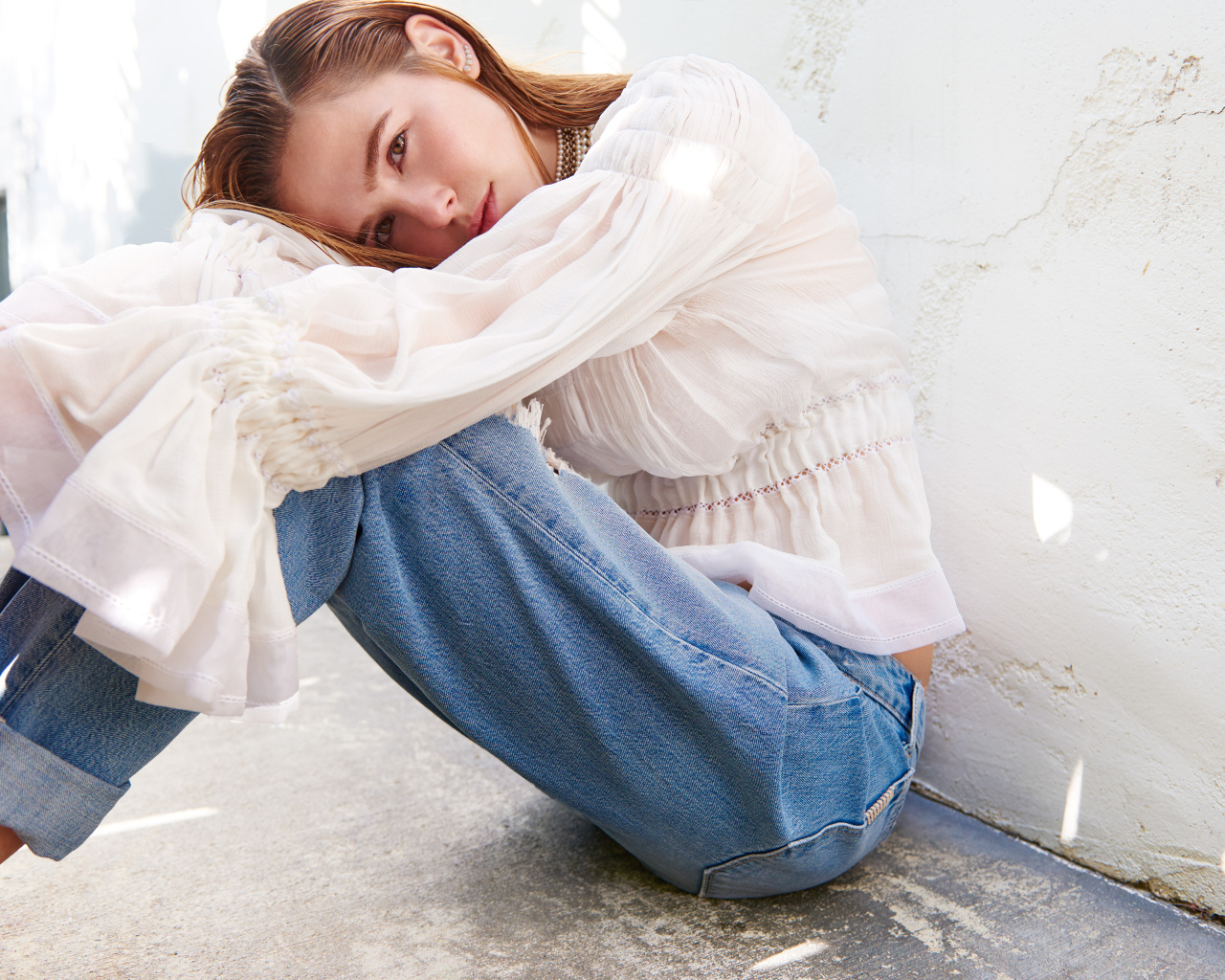 Актриса Зои Дойч сидит у стены