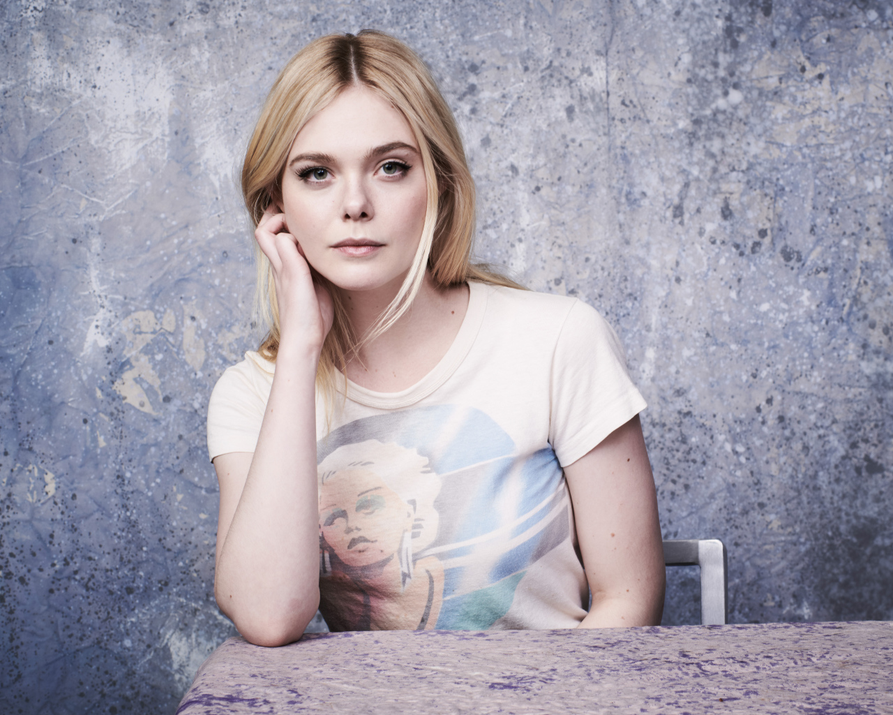 Красивая актриса Эль Фаннинг сидит за столом