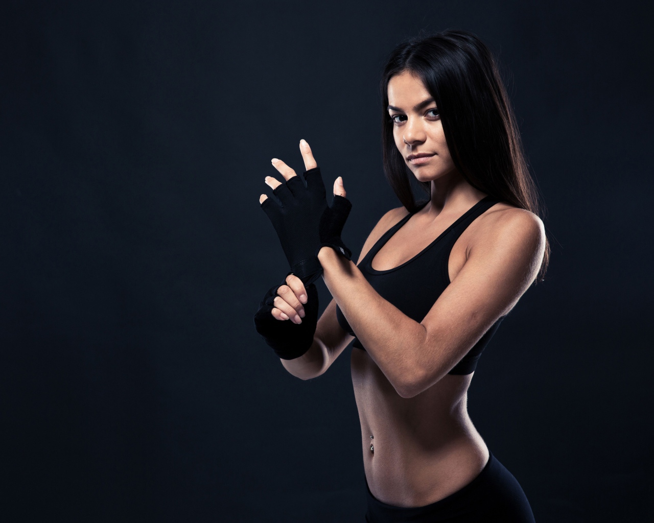 Красивая спортивная девушка в перчатках на сером фоне