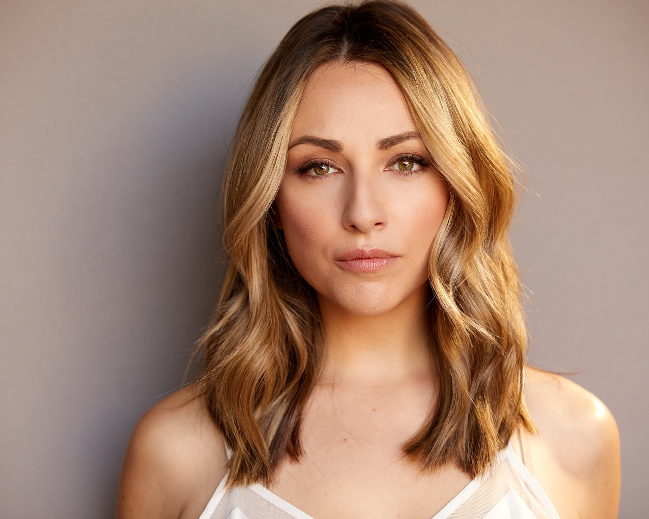 Красивая блондинка Никки Поснер на сером фоне 