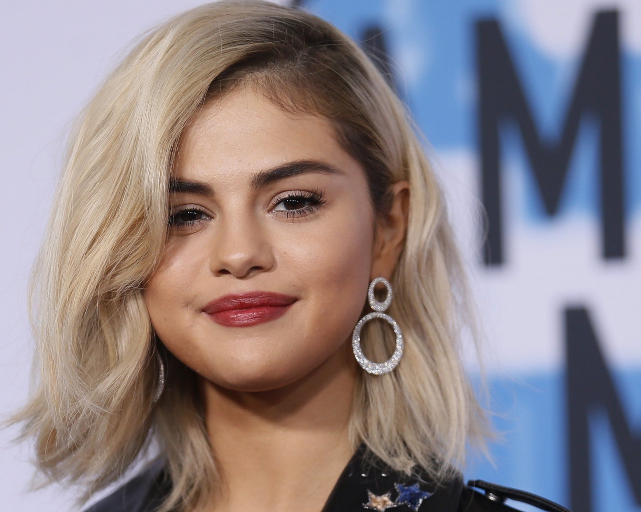 Красивая блондинка, актриса Селена Гомес с серьгами в ушах