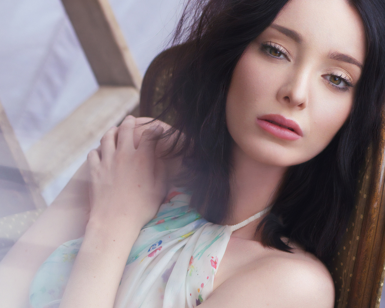 Красивая брюнетка, актриса Эмма Дюмон сидит на стуле 