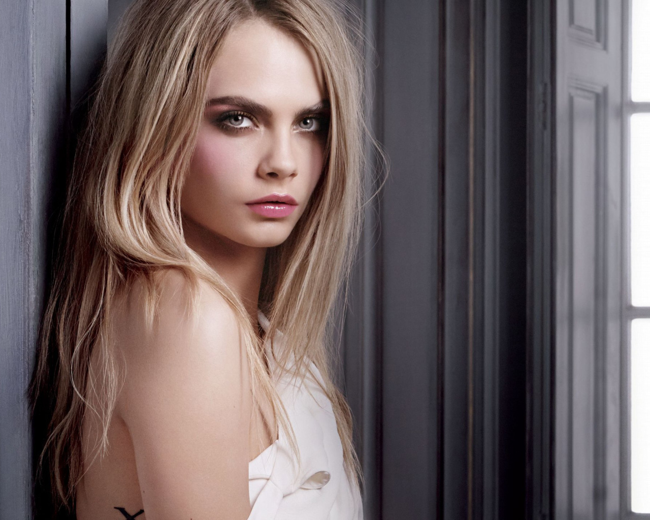 Красивая девушка, актриса Кара Делевинь у стены