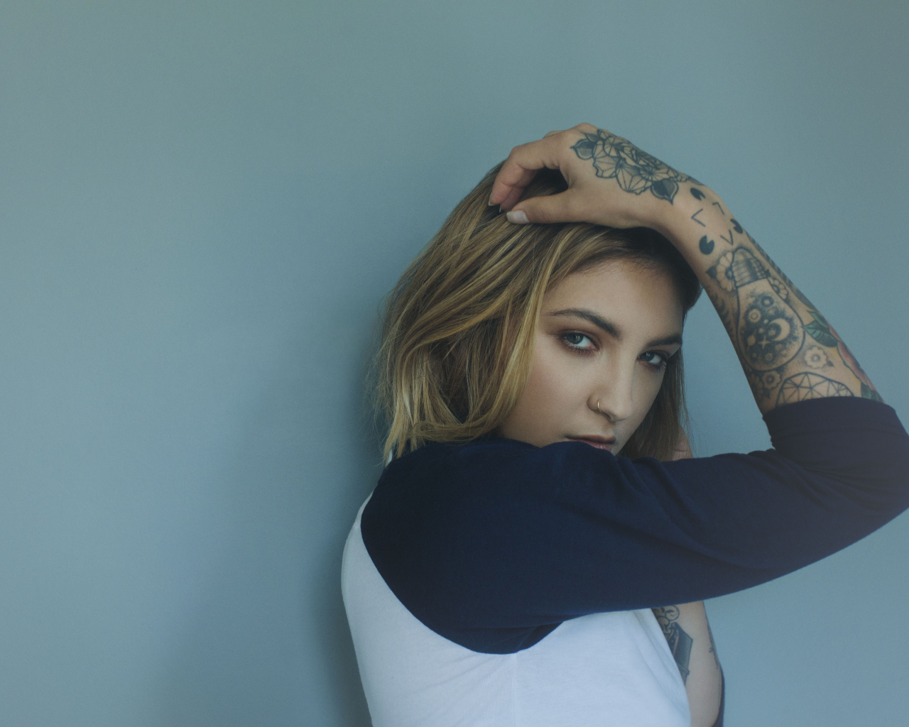 Красивая девушка стоит с татуировками на руке 