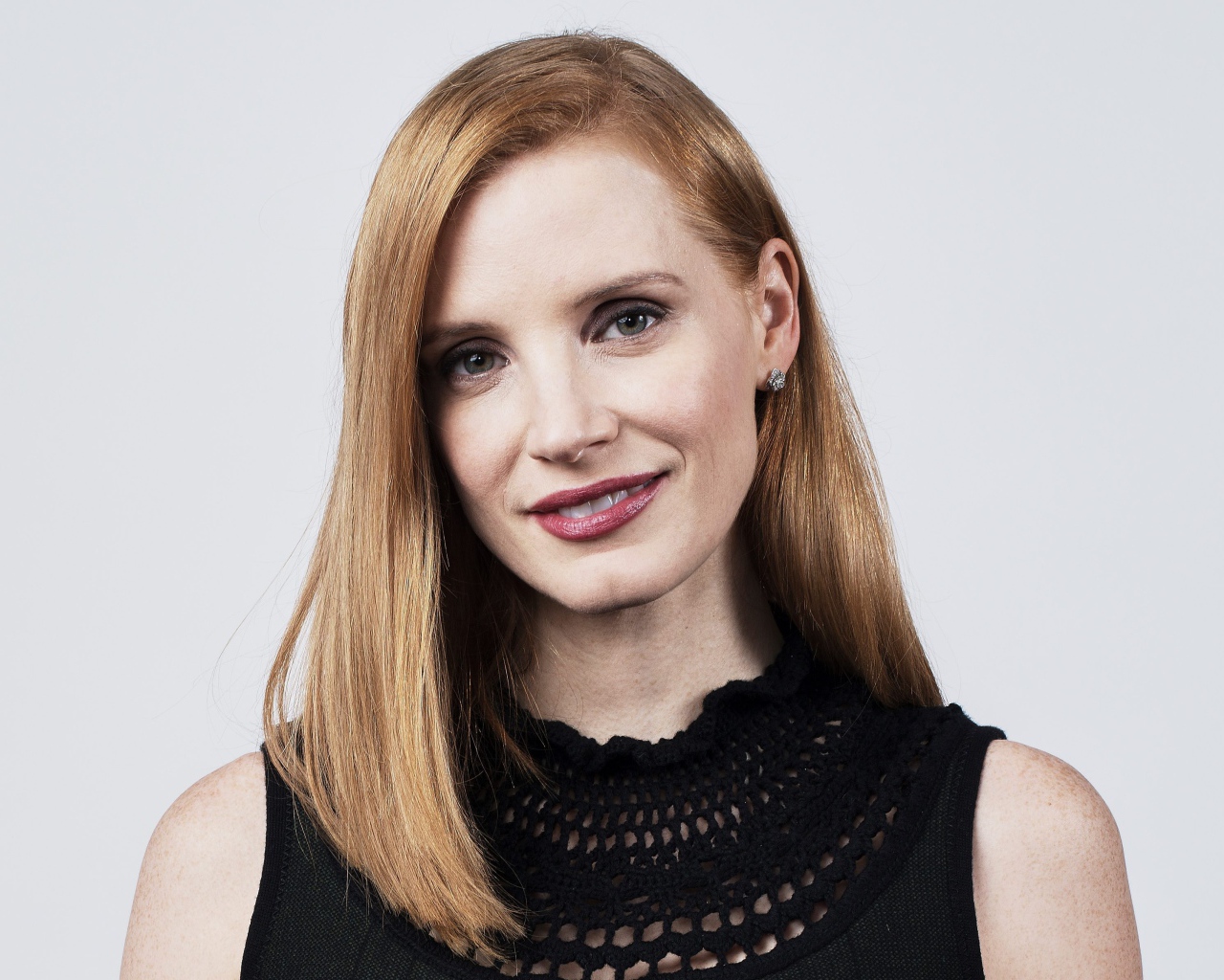 Красивая рыжеволосая актриса Джессика Честейн на сером фоне