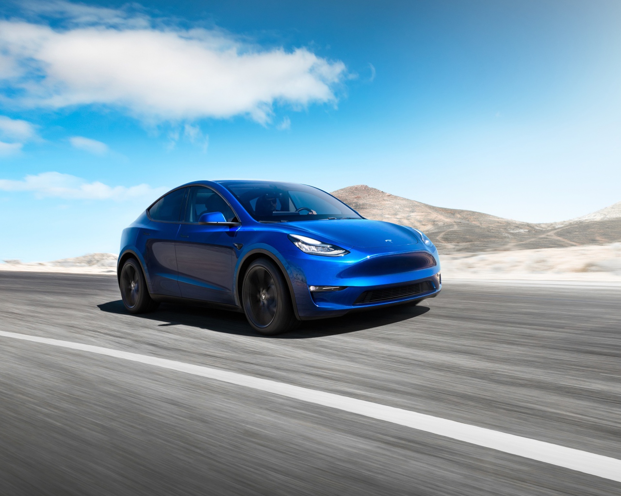 Синий автомобиль Tesla Model Y 2020 года на фоне голубого неба
