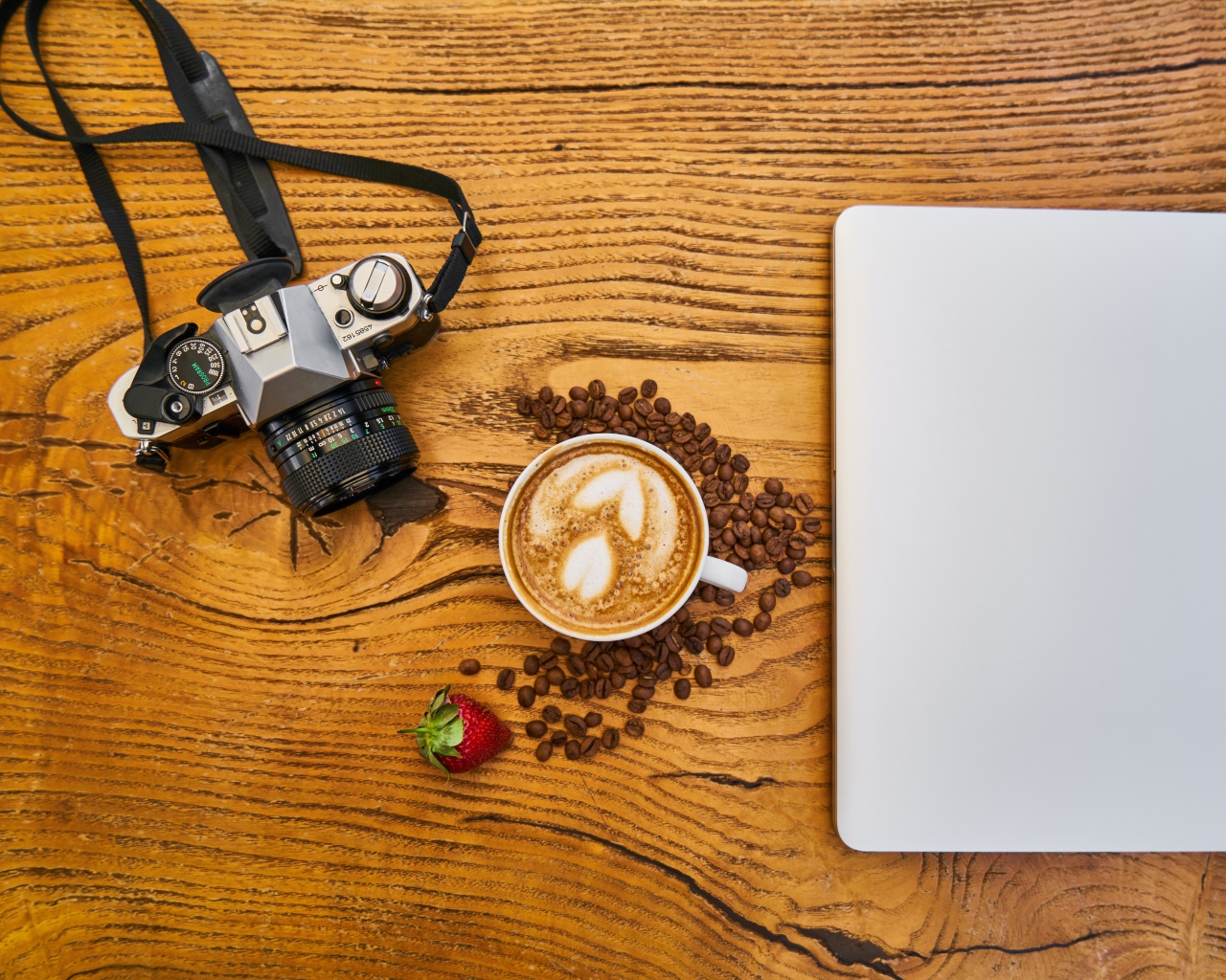 Cup of coffee on a table with a camera and laptop