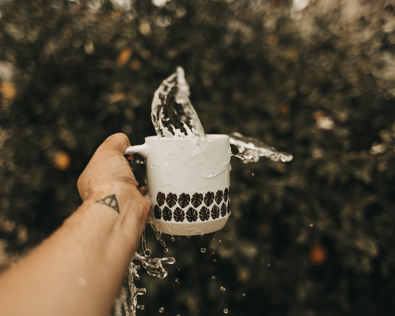 Чашка с водой в руке с татуировкой 