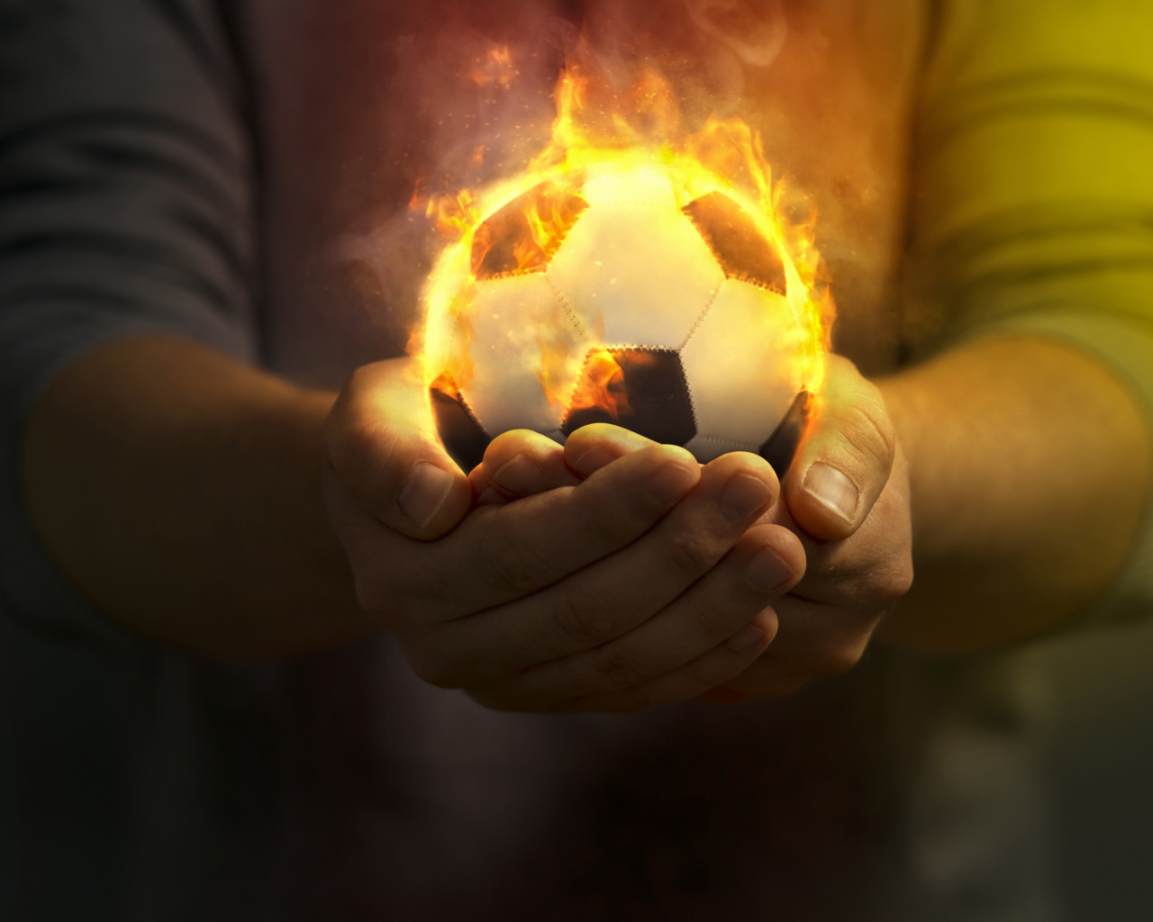 Огненный футбольный мяч в руках 