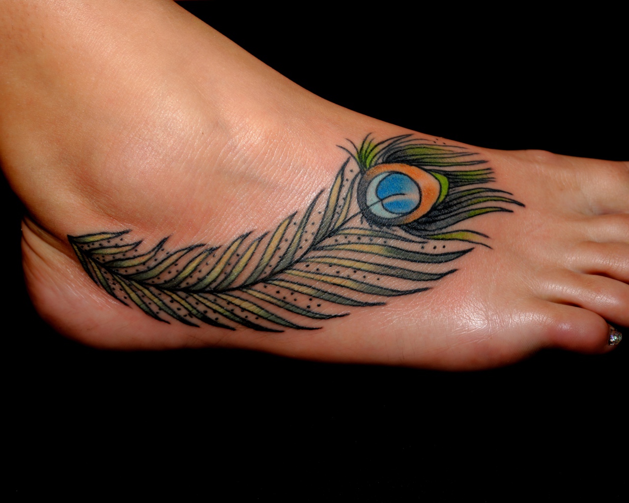Татуировка перо павлина на ноге на черном фоне