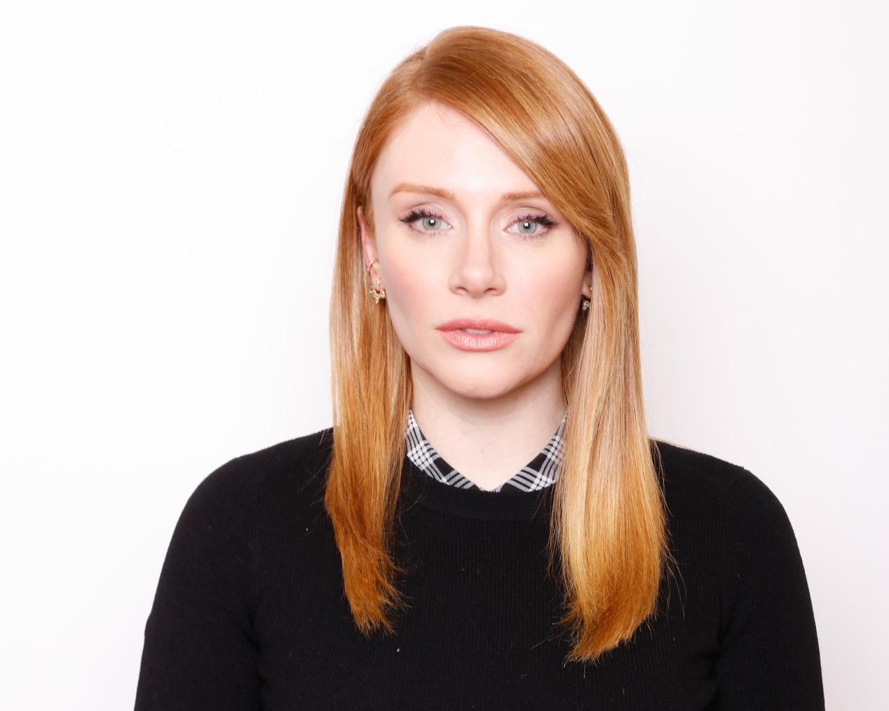 Рыжеволосая актриса Брайс Даллас Ховард в черном свитере на белом фоне