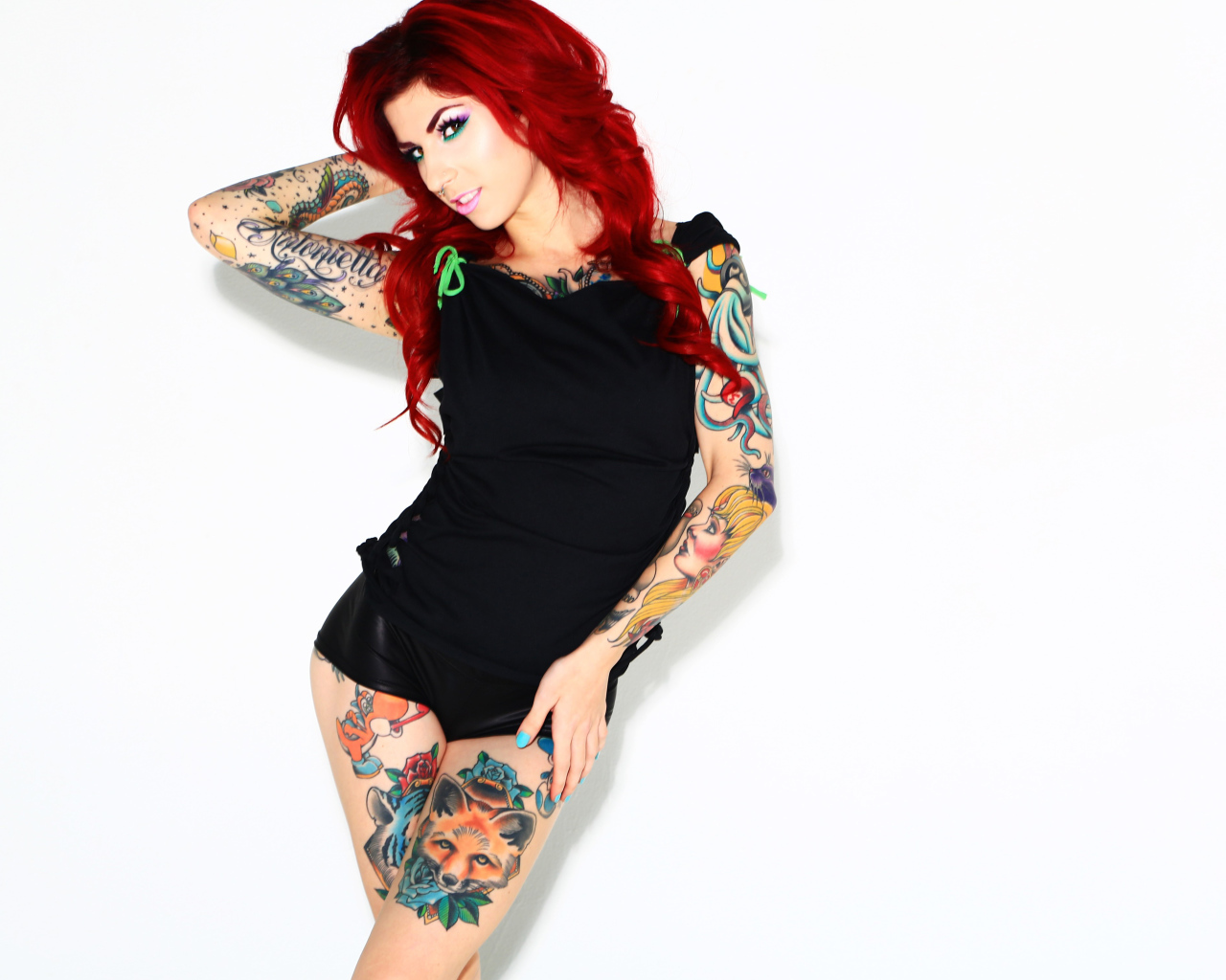 Рыжеволосая девушка с татуировками на теле на белом фоне