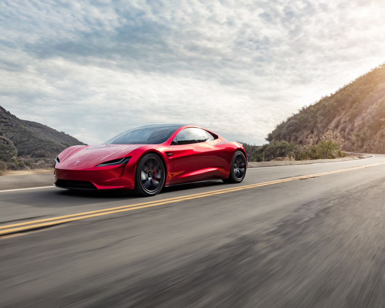 Красный автомобиль Tesla Roadster едет по трассе 