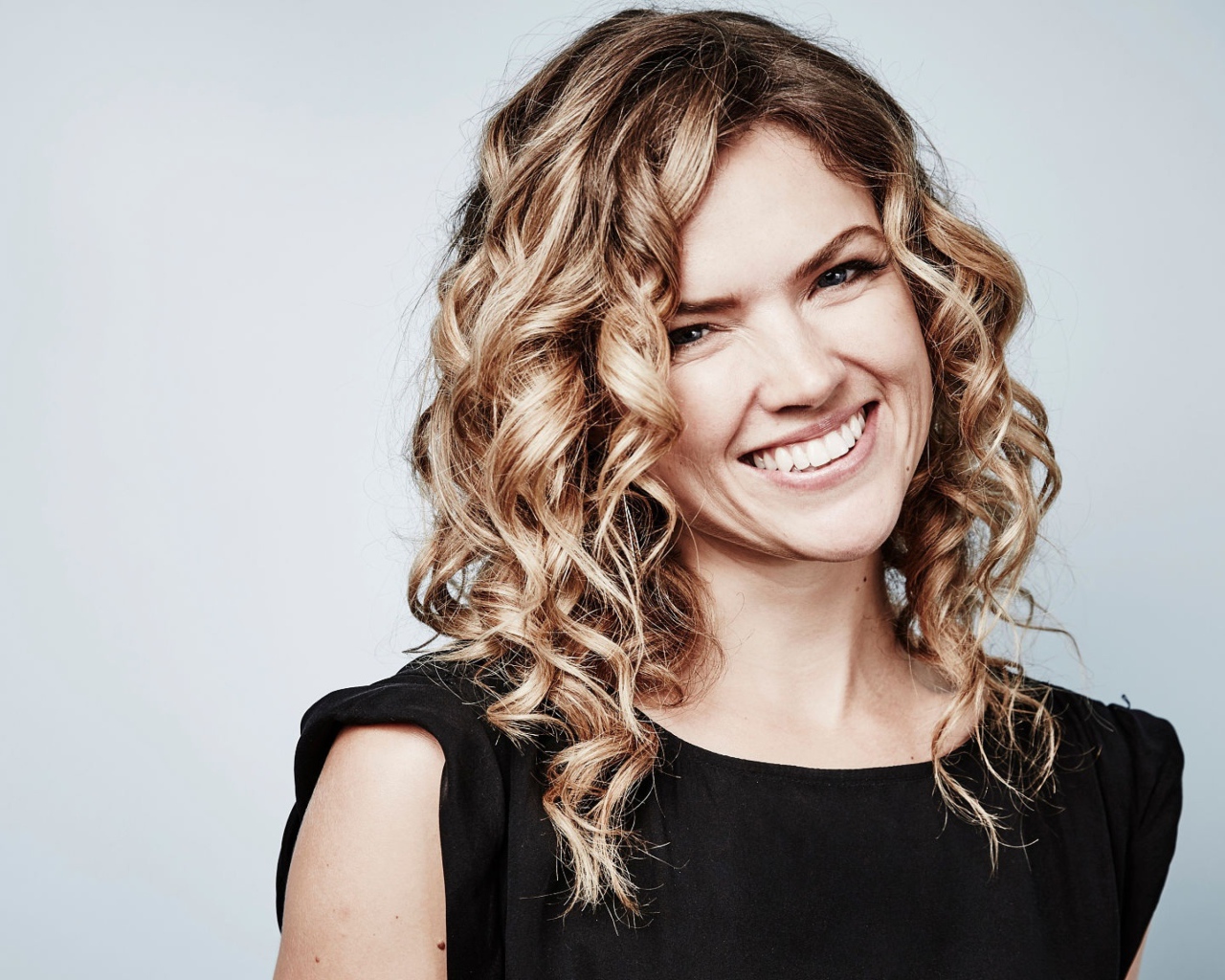 Улыбающаяся блондинка, актриса Эрин Ричардс на сером фоне