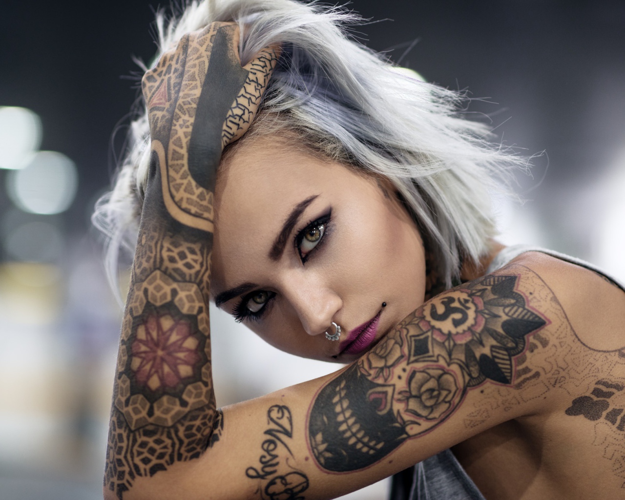 Татуировки на теле красивой девушки с пирсингом в носу
