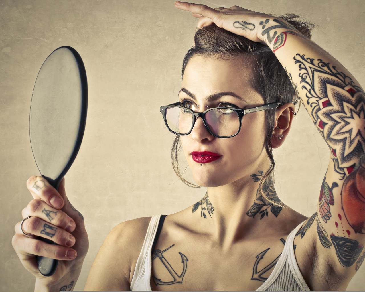 Девушка с татуировками на теле смотрит в зеркало