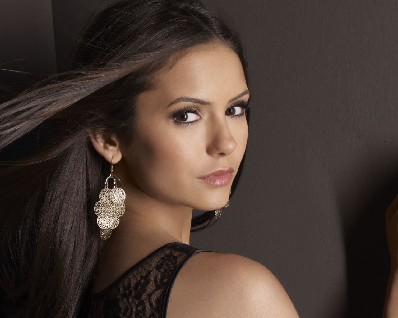 Ветер развивает волосы актрисы Нина Добрев на фоне стены