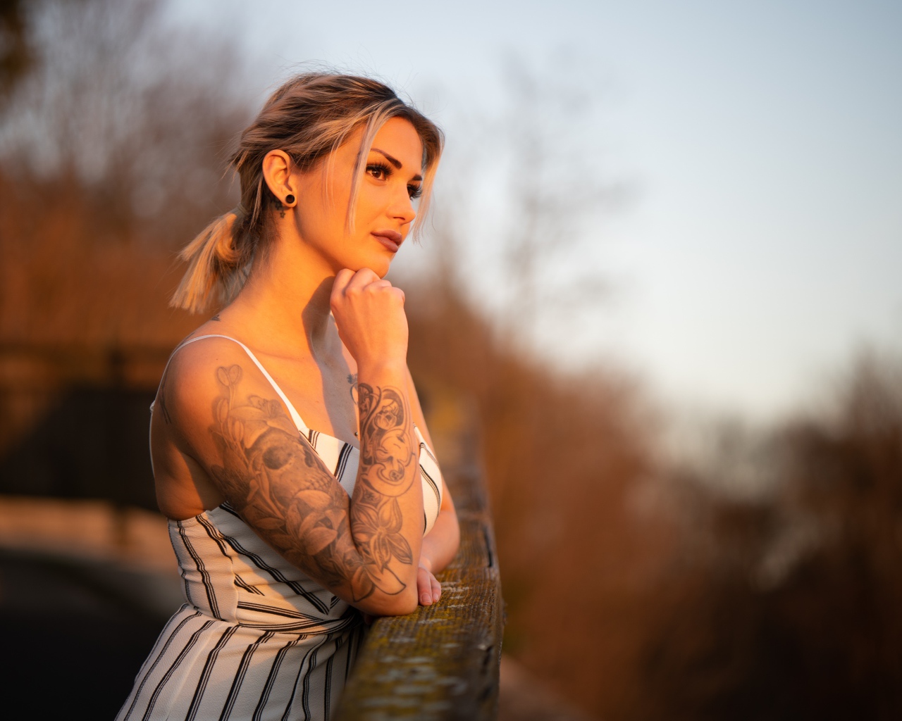 Молодая девушка с татуировкой на руке в лучах солнца