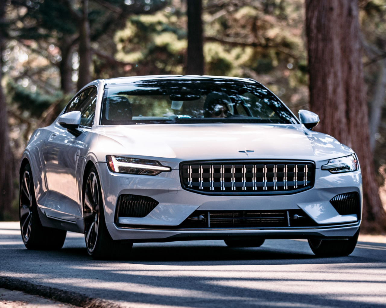 Белый автомобиль Polestar 1 2021 года едет по дороге