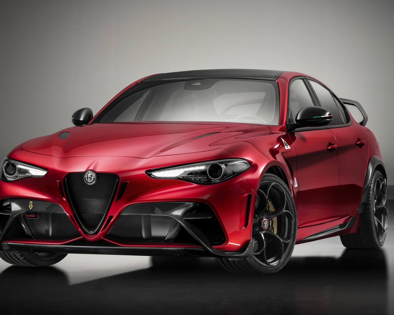 Красный автомобиль Alfa Romeo Giulia GTAm 2020 года на сером фоне
