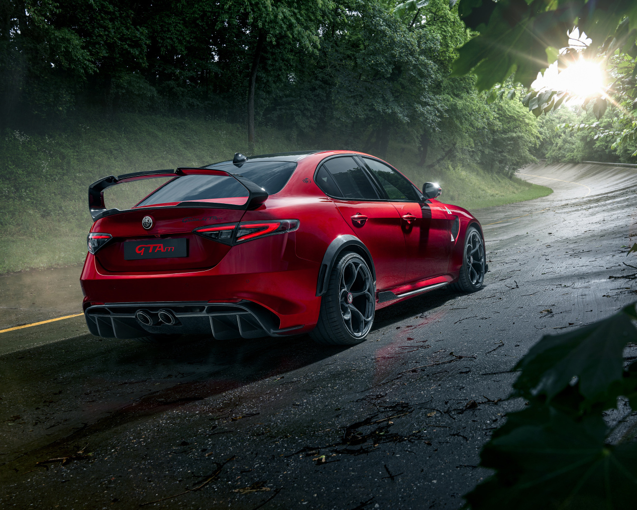 Красный автомобиль Alfa Romeo Giulia GTAm, 2021 года на дороге в лесу