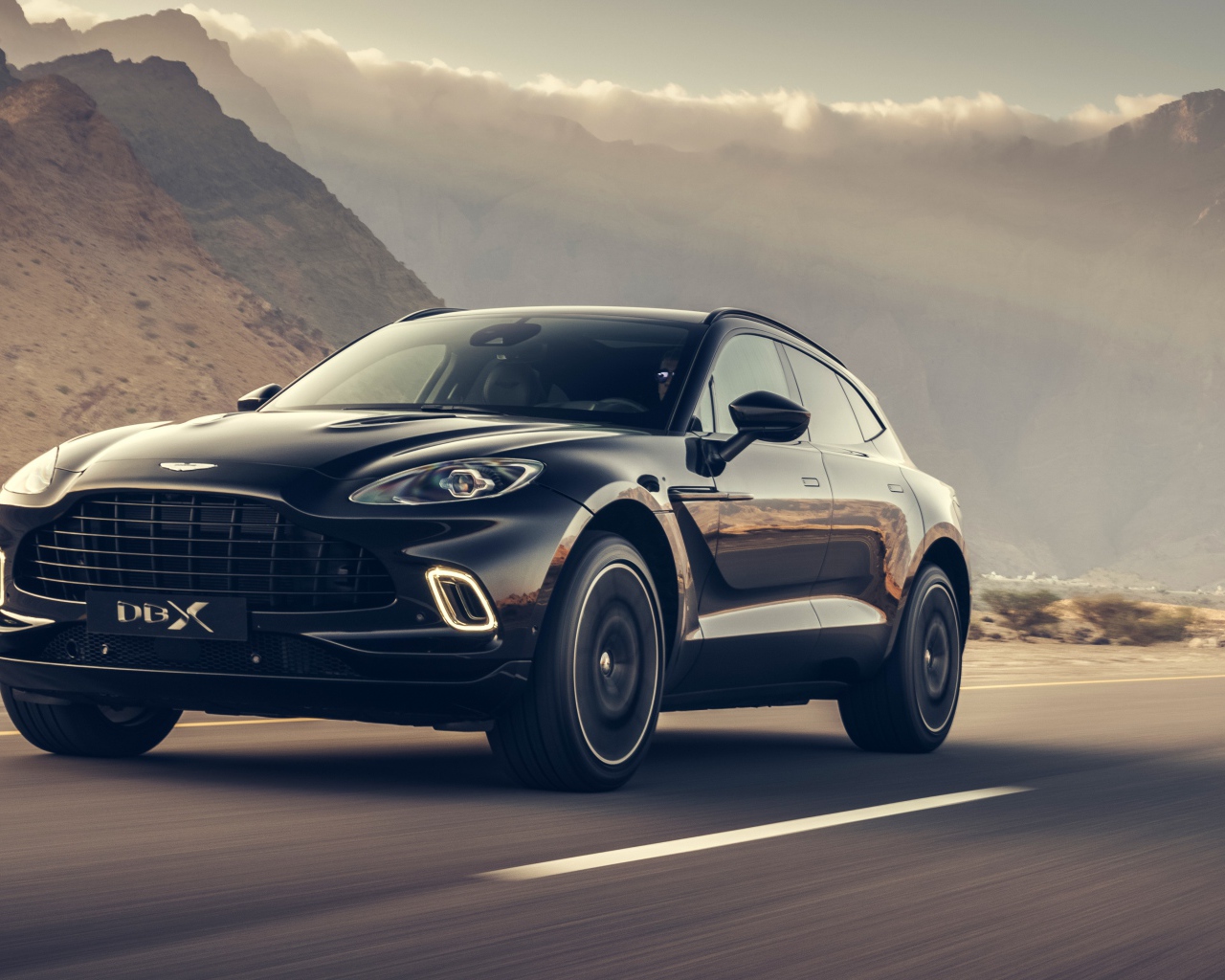 Черный автомобиль Aston Martin DBX 2020 года на трассе