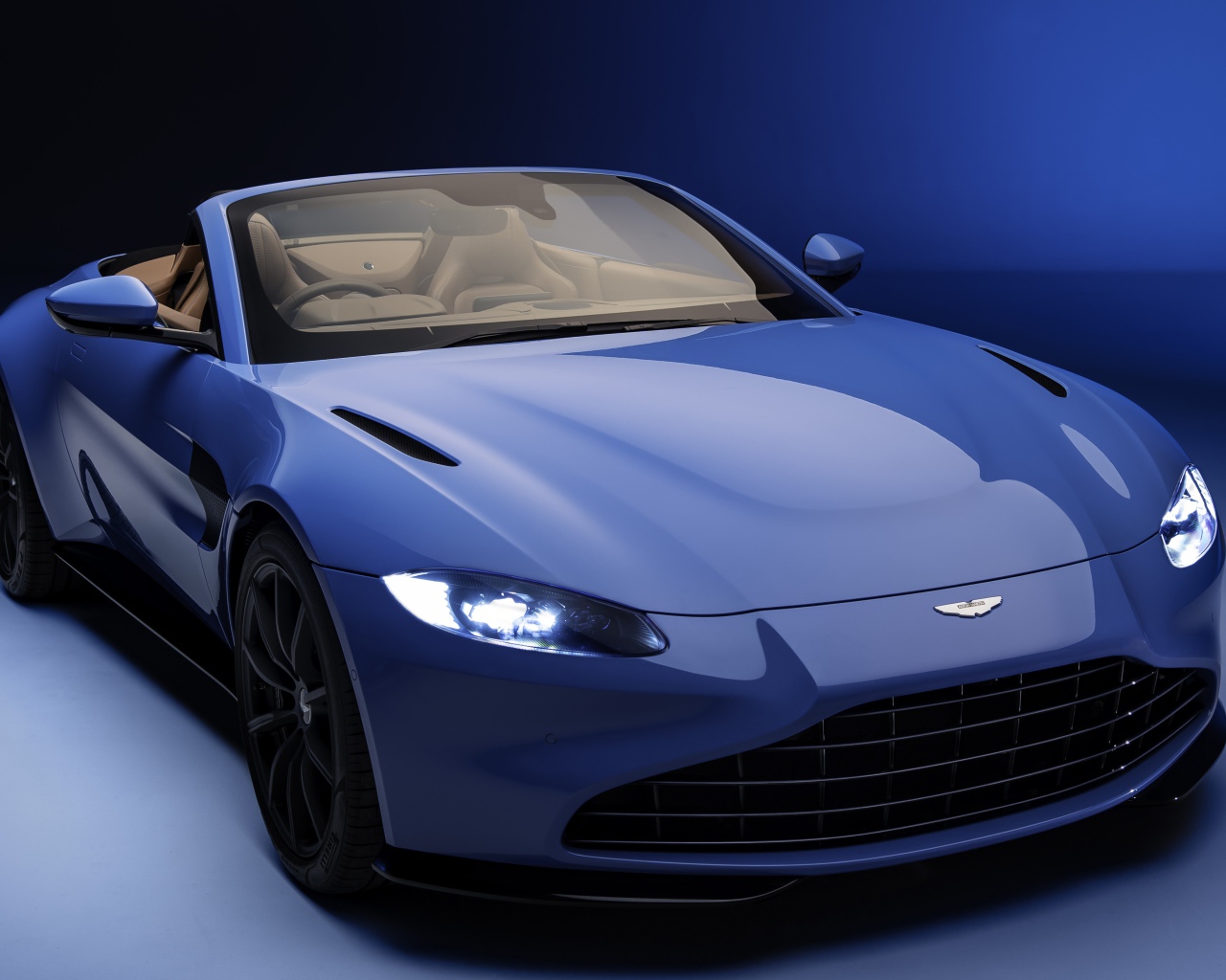Кабриолет Aston Martin Vantage Roadster 2020 года на синем фоне