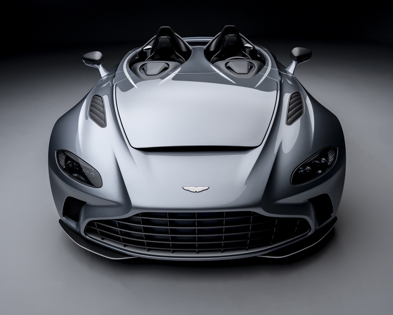 Серебристый автомобиль Aston Martin V12 Speedster 2020 года на сером фоне