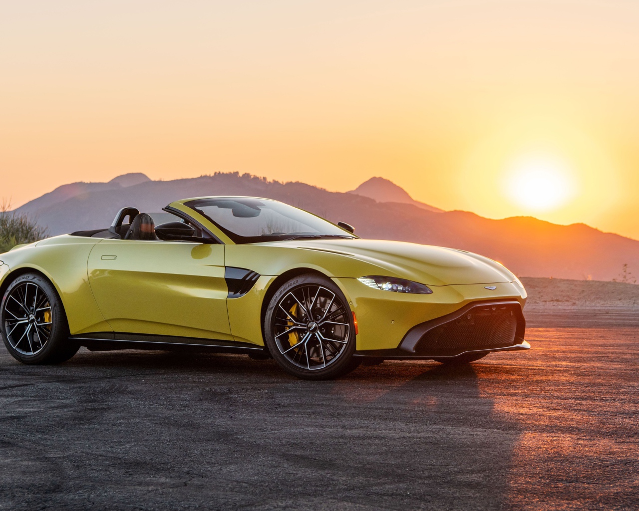 Желтый автомобиль  Aston Martin Vantage Roadster, 2021 года на закате