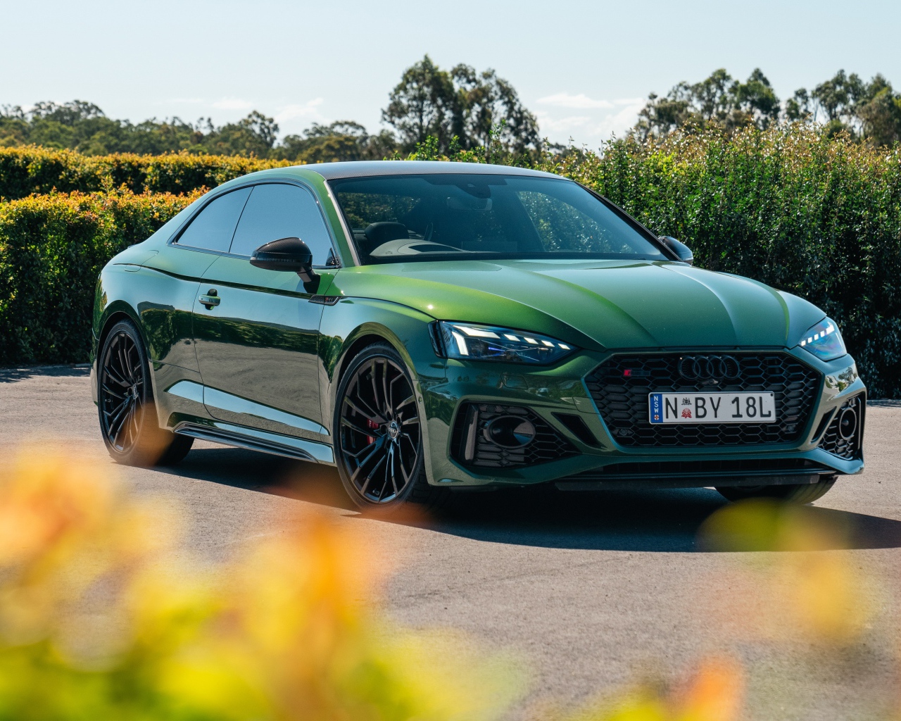 Зеленый автомобиль Audi RS 5 Coupé 2020  года в лучах солнца