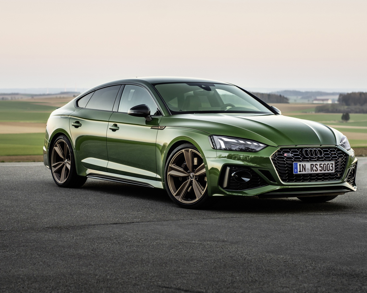 Зеленый автомобиль Audi RS 5 Sportback 2020 года на фоне поля