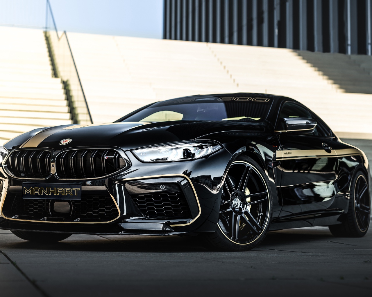 Черный автомобиль BMW Manhart MH8 800 2020 года у лестницы 