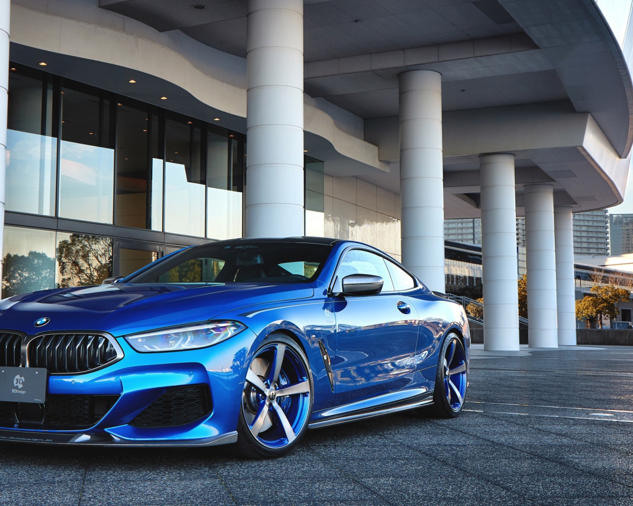 Синий автомобиль BMW M850i XDrive Coupe 2020 года у здания 