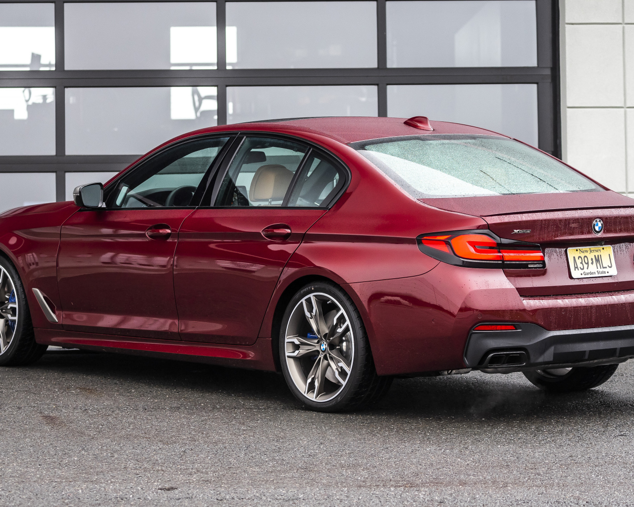 Красный автомобиль BMW M550i XDrive, 2021 года вид сзади