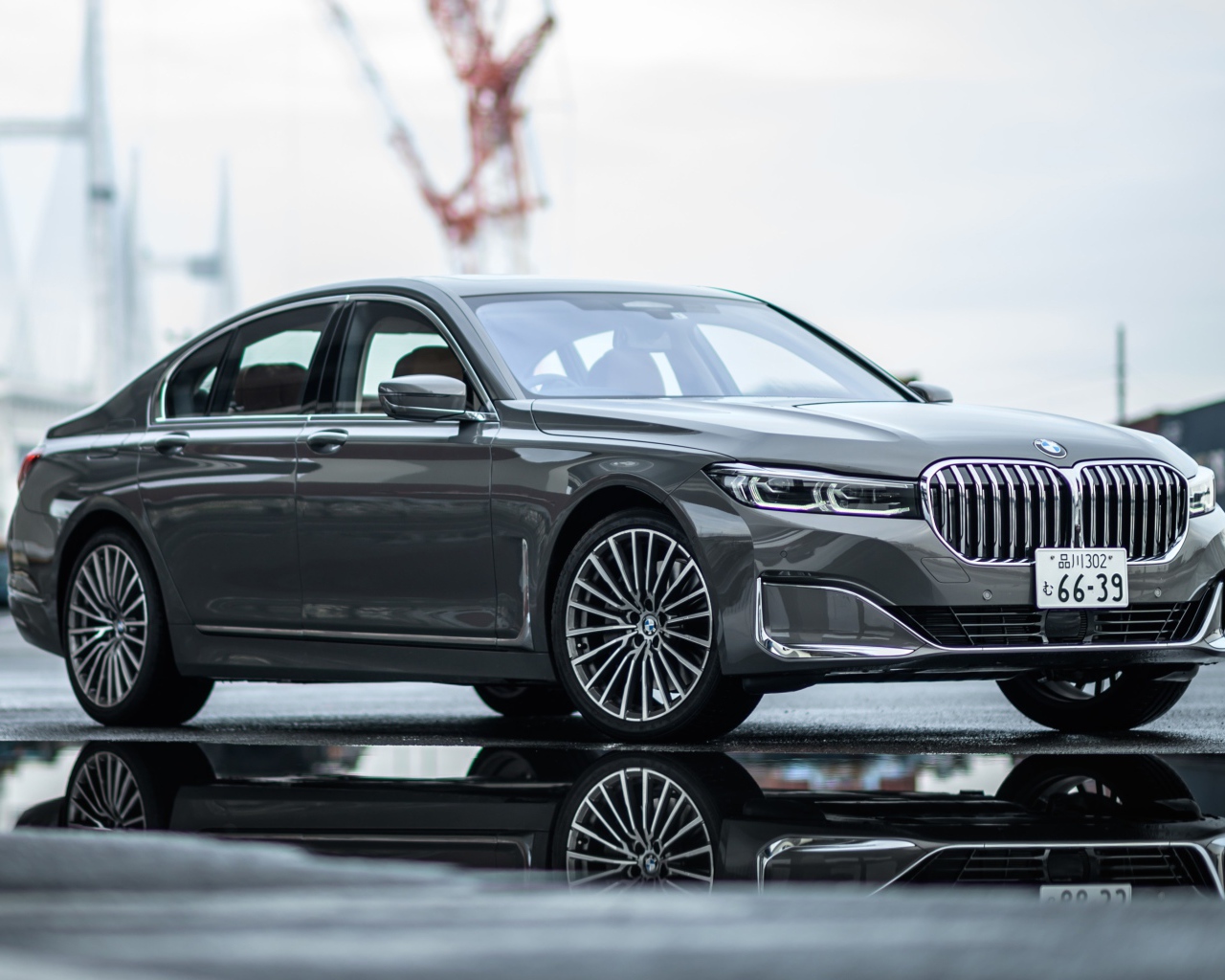 Серебристый автомобиль BMW 745e на мокром асфальте 
