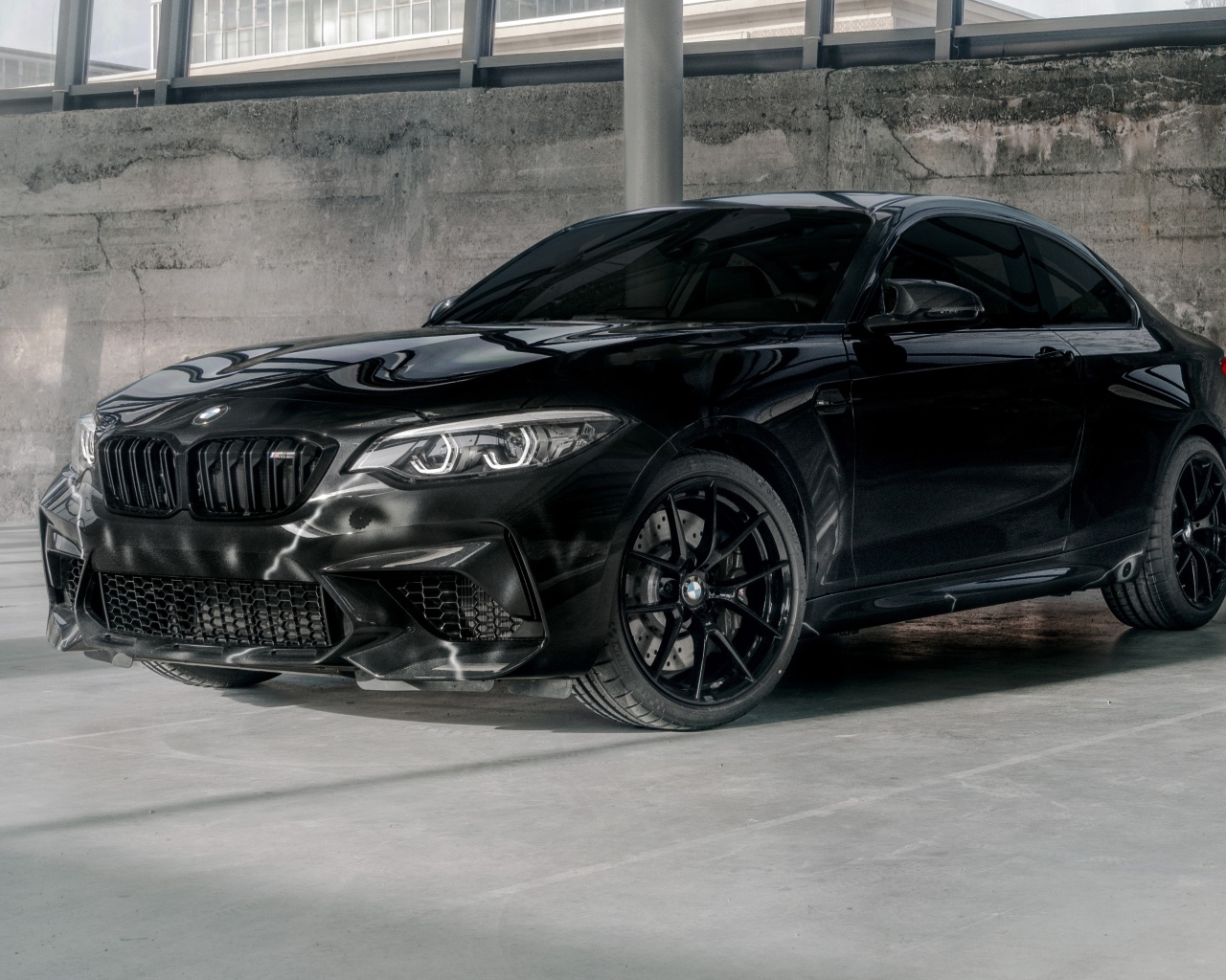 Черный автомобиль  BMW M2, 2020 года у бетонной стены