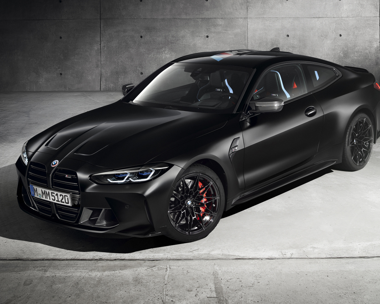 Черный автомобиль BMW M4 Competition X Kith 2020 года на фоне серой стены
