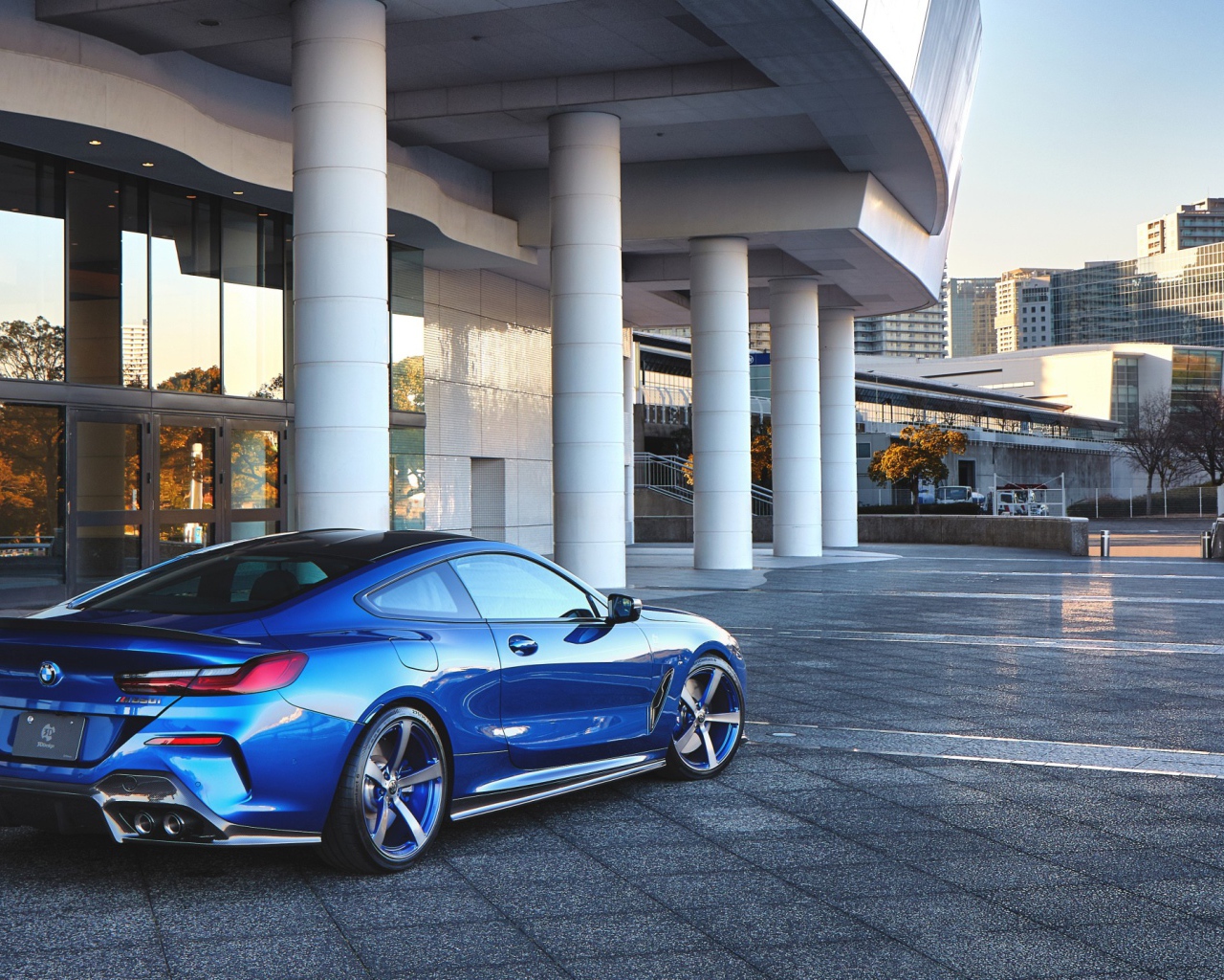 Синий автомобиль BMW M850i XDrive Coupe 2020 года у здания вид сзади