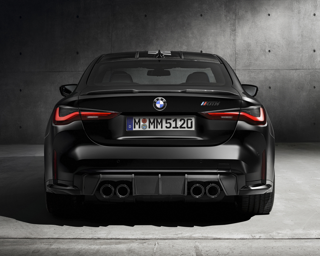 Черный BMW M4, 2021 года вид сзади на сером фоне