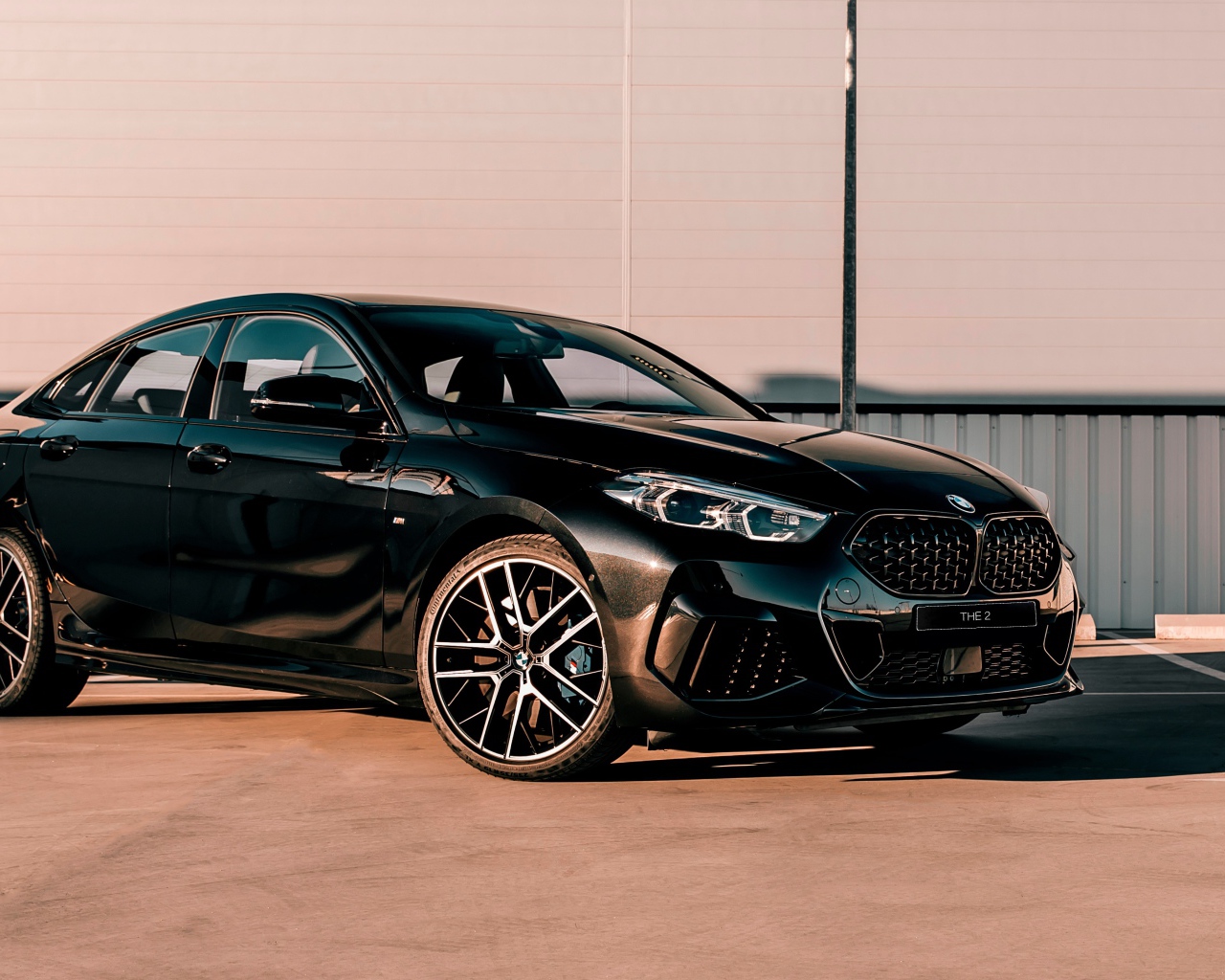 Черный автомобиль BMW M235i XDrive Gran, 2020 года у белого здания 