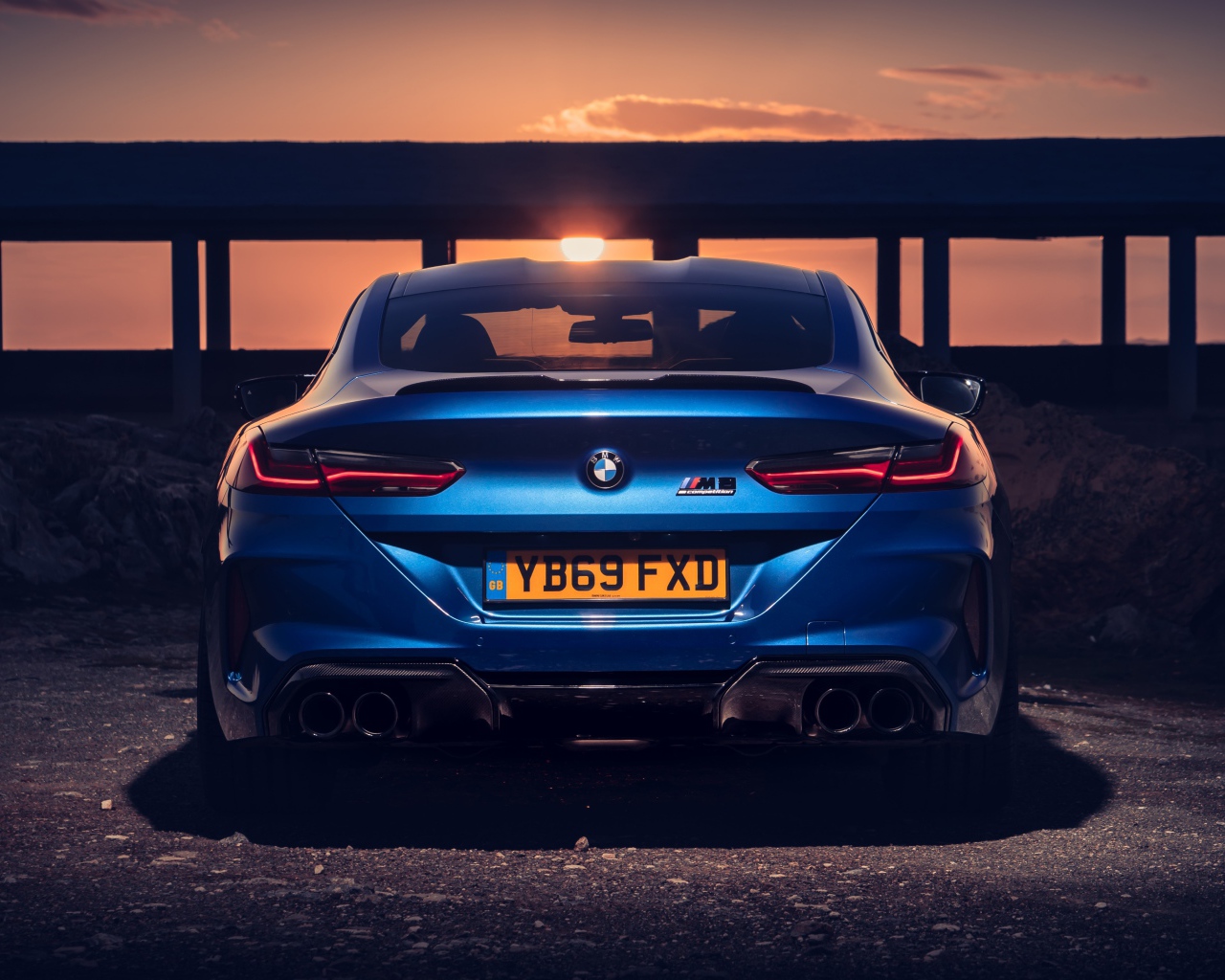 Синий автомобиль BMW M8, 2019 года на фоне заката 